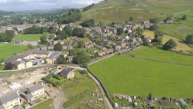 Slow forward moving drone footage over part of Settle village rural North Yorkshire, UK. The footage then pans and focuses on some stone houses. Includes footage of countryside, hills and fields