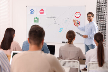 Teacher explaining traffic rules to audience during lesson in driving school