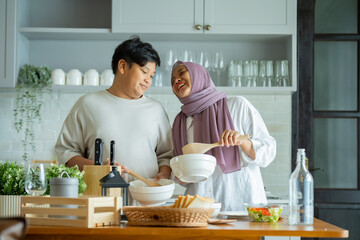 Cute son And His Muslim Mom In Hijab Preparing Pastry For Cookies In Kitchen, Baking Together At Home. Islamic Lady With son Enjoying Doing Homemade Pastry, preparing to cook breakfast for her family.