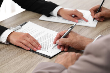 Manager showing client where he must to mark signature at light wooden table indoors, closeup