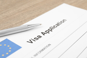 Immigration to Europe. Visa application form and pen on wooden table, closeup