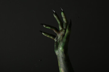 Scary monster on black background, closeup of hand. Halloween character
