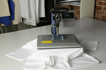 Printing logo. Heat press with t-shirt on white table