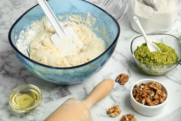 Making delicious pesto bread. Raw dough and ingredients on white marble table