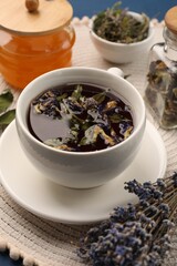 Aromatic tea with different dry herbs and honey on table, closeup