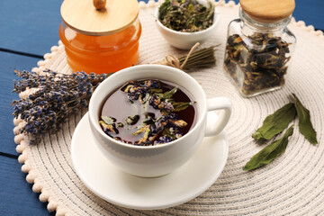 Aromatic tea with different dry herbs and honey on blue wooden table, closeup