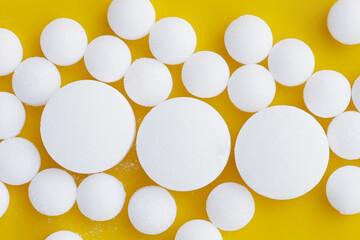 White mothballs on yellow background.