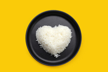 Cooked white rice in black plate on yellow background.