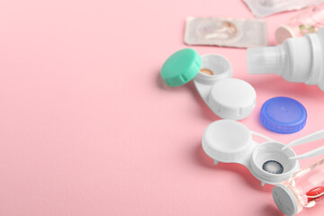 Cases with color contact lenses, bottle of solution and tweezers on pink background, space for text