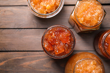Delicious apple jam in jars on wooden table, flat lay. Space for text