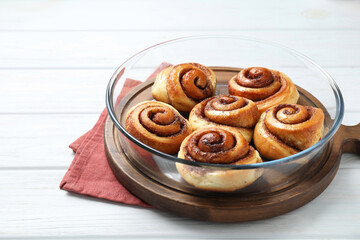 Tasty cinnamon rolls on white wooden table