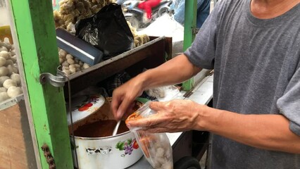 Preparing cilok. View of a penjual clilok seller who is making cilok food for the buyer. Cilok is a typical food from West Java, Indonesia.