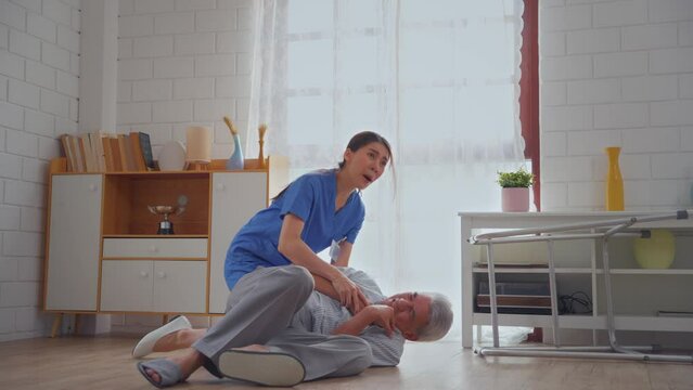 Asian caregiver helping senior male from falling on the ground at home. 