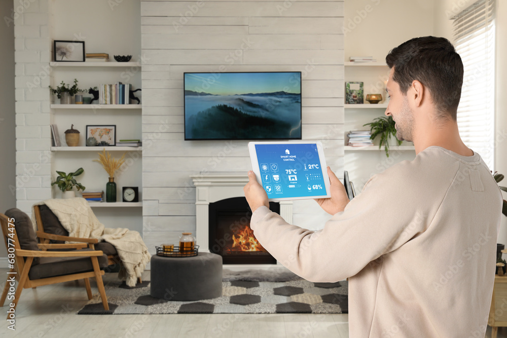 Poster man using smart home control system via application on tablet indoors