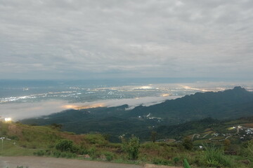 Fototapeta premium Path up the mountain at night with lights from villages along the road on both sides The village must be in the middle of a valley. There are forests and complete nature.