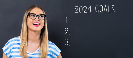 2024 goals with happy young woman in front of a blackboard