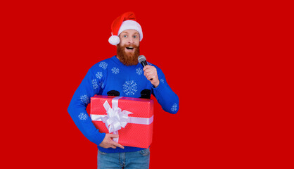 New Year holiday shopping sale. Happy 2024 New Year. Christmas shopping sale. Xmas sale announcement. Santa man with microphone and gift isolated on red. Christmas present. Copy space