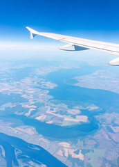 Aerial view from airplane window above green ground. View from the airplane window with beautiful clouds at sunrise