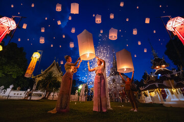 Young women releasing sky lantern into the night sky in yi peng festival. Floating lanterns ceremony or Yeepeng ceremony, traditional Lanna Buddhist ceremony in Chiang Mai, Thailand. lanterns at dusk