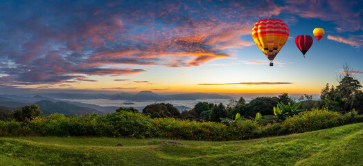 Panoramic view. Colorful hot-air balloons flying over the mountain with sea fog, mist and red...
