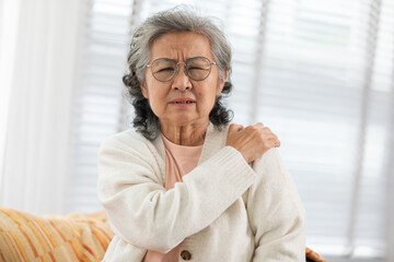 Asian Elderly senior woman with white hairs neck and shoulder pain and illness on sofa alone at...