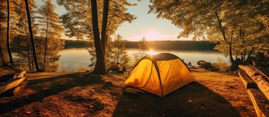 camping with a tent on the lake bank in early morning. morning sunlight touches against forest hill