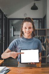 Smiling woman holding digital tablet with blank white desktop screen for product display, Mockup digital tablet with blank screen.