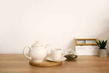 Teapot, cup and tea leaves on white kitchen counter