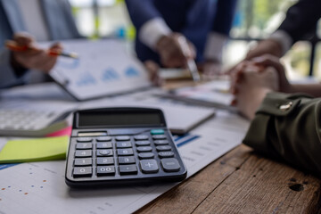 Group of confident business people point to graphs and charts to analyze market data, balance sheet, account, net profit to plan new sales strategies to increase production capacity.	