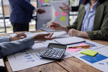 Group of confident business people point to graphs and charts to analyze market data, balance sheet, account, net profit to plan new sales strategies to increase production capacity.	