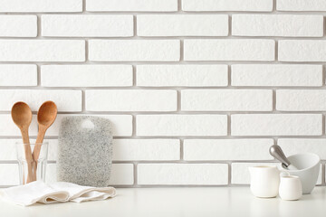 Kitchen utensils on table near white brick wall