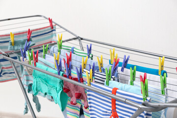 Clean baby clothes hanging on dryer, closeup