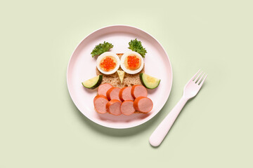 Plate with funny children's breakfast in shape of owl on green background