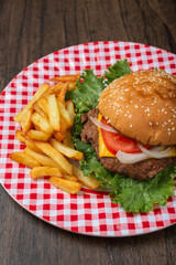 Homemade hamburger with fries on a wooden table.