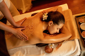 Woman customer having exfoliation treatment in luxury spa salon with warmth candle light ambient....