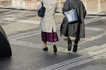 冬の街の道路で歩く二人のシニア女性の姿