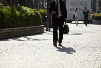 Obraz premium 朝の通勤時間の街で歩く男性サラリーマンの姿