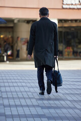 冬の朝の繁華街で歩く一人の男性サラリーマンの後姿
