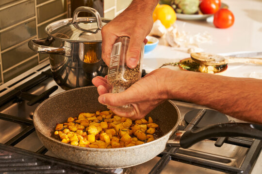 Man pouring seasoning into hand at stove