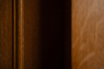 Details of the texture on historic wood paneling, with dramatic shadows around a corner. The closeup shows off the rich, warm wood grain in the interior of a historic mansion.
