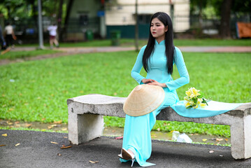 A young girl wearing a jade-green ao dai the traditional costume of Vietnam. Photo for tourism,...