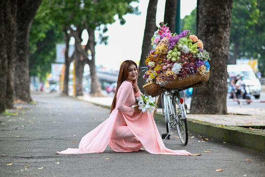 A young girl wearing a lotus pink color ao dai the traditional costume of Vietnam. Photo for tourism, culture, tradition, and the beauty of Asian people. Idea for train model in computer vision system