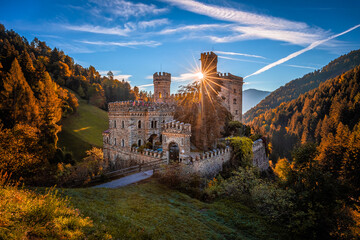 Latzfons, Italy - Beautiful autumn scenery at Gernstein Castle (Castello di Gernstein, Schloss Gernstein) at sunrise in South Tyrol with blue sky, sunrays and golden foliage - obrazy, fototapety, plakaty