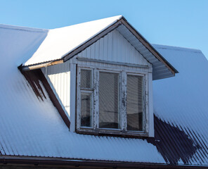 Roof of a house covered in snow against a blue sky