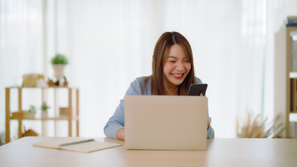 Funny euphoric young asian woman celebrating winning or getting ecommerce shopping offer on computer laptop. Excited happy girl winner looking at notebook celebrating success - obrazy, fototapety, plakaty