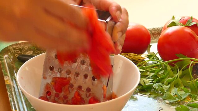 Detail of female hand grated tomato for preparation of typical Valencian paella.