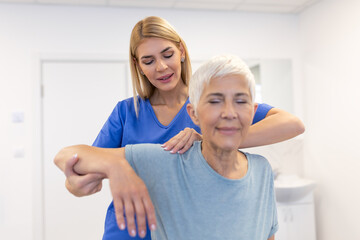 Doctor or Physiotherapist working examining treating injured arm of senior female patient,...