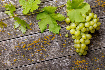 Grape with vine leaves on wooden table