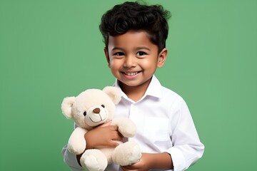 Adorable Fictional Little Child in Plain Casual Shirt Holding a Teddy Bear and Smiling. Isolated on a plain green background. Generative AI.