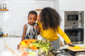Portrait of enjoy happy love african american family mother and african little boy son child having fun help cooking food healthy eat together with fresh vegetable salad and ingredient in kitchen